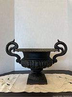 Front view of cast iron planter showing overall shape, fluted body, and handles