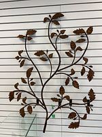 Full view of metal branch wall decor showing overall shape and size against slat wall.