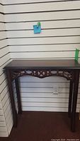 Front view of small wood sofa table showing top and carved front decorative panel.