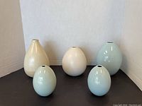 Five blue, white, and cream vases displayed on a black surface.