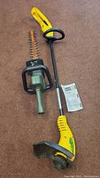 Electric weed trimmer and hedge trimmer side by side on carpet.