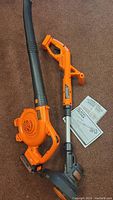 Black & Decker weed trimmer and leaf blower displayed with instruction manuals on carpet