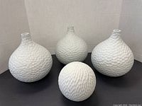 Front view of 3 white ceramic vases and 1 textured ceramic ball showing size and texture