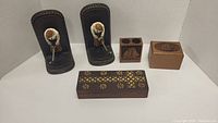 Photo showing the full lot of two golf motif leather bookends and four decorative wood boxes in various sizes and carvings.