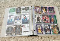 Photo of two binder pages showing multiple NBA basketball cards including LeBron James and other legendary players.