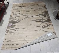 Full view of carpet showing abstract white and grey linear pattern on neutral background