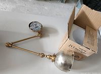 Side view of the extendable arm wall light with glass cup shade and original box beneath it.