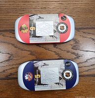 Two unopened metal cases for NHL All-Stars 2013 stamp and medallion sets, one red (Chicago Blackhawks - Bobby Hull) and one blue (New York Islanders - Denis Potvin) on wood surface.