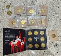 Full view of the coin set booklet along with nine additional individually wrapped coins laid out on a granite surface.