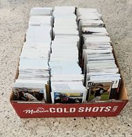 Top down view of a red box labeled Molson Cold Shots Lager filled with multiple stacks of baseball cards.