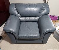 Front-facing photo of a custom made leather armchair in blue-grey color showing the seat cushion, armrests and backrest.