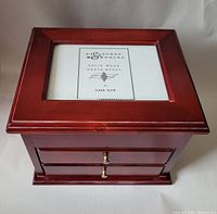 Front view of solid wood photo jewelry box showing photo frame on lid and two drawers below.