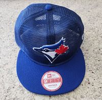 Front view of blue Toronto Blue Jays snapback hat with mesh back and flat brim, showing embroidered team logo and original sticker on brim.
