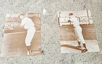 Two vintage sepia-tone posters of Mickey Mantle at the ballpark displayed on countertop with a glass jar for size reference