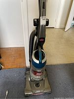 Full upright vacuum cleaner showing blue and gray body and handle.