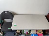 Folding table and padded folding chair set placed next to each other against a wall.