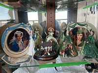 Showcase of Gone With The Wind collectibles: two plates, four figurines, and Home of Tara music box miniature with certificates of authenticity beneath.