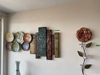 Photo showing all three metal wall decor items including the multicoloured plates and panels, and the flower-shaped candle holder with glass tea lights