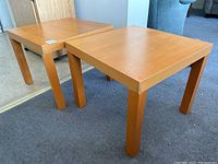 Pair of square wooden end tables with screw-in legs, positioned on carpeted floor.