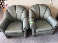 Pair of green-gray upholstered Sklar Pepplar armchairs with shell-back design and visible wear on arms and seats.