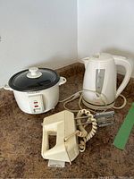 Photo showing the Sunbeam electric kettle, Proctor Silex rice cooker, and Sunbeam electric beater together on a brown countertop.