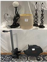 Photo showing five lamps and one rowing machine together on a white draped surface and blue rug.