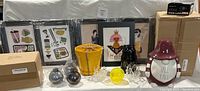 Photo showing all items including framed artwork in background, ceramic planter pot, black ceramic cat canister, maroon-hatted gnome canister, decorative yellow orb and glass geometric pieces.