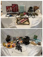 Lot of assorted tools and hardware including pliers, wrenches, cords, plumbing valves, electrical parts and a light fixture shown on white cloth background.