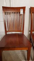 Front view of one of the wooden dining chairs showing slatted backrest, seat, and legs.