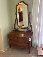 Side view of antique wooden dresser showing the mirror supported on both sides and the rounded edges of dresser top.