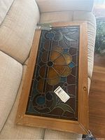 Overall angled view of antique stained glass panel showing flower design, wooden frame, and condition.