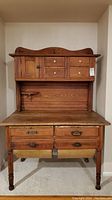 Full front view of vintage oak baker’s cabinet showing upper hutch, lower drawers and bins