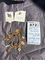 Overview of gold-tone charm bracelet with nursing graduate theme and guardian angel pin, with handwritten note