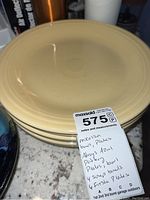 Stack of 6 pale yellow Fiesta Ware plates showing their shape and color.