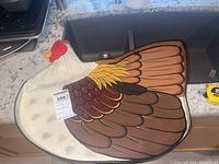 Hen-shaped wooden serving tray with painted detailed feathers in brown, yellow, white, red.
