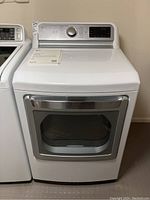 Full front view of the white LG clothes dryer showing chrome handle and top control panel with dial and display.