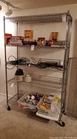 Complete view of metal shelving unit with four wire shelves, caster wheels, and various items on shelves (items not included).
