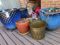Two navy blue glazed basketweave planters, terra cotta planter, gold metal planter on deck