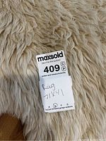 Close-up of sheepskin showing soft, curly cream wool fibers with a label indicating dimensions 71x41 inches