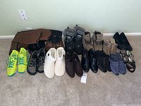 Wide view showing all shoes arranged against wall on carpet with labels