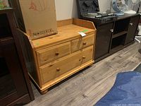 Wood cabinet showing full front, with three drawers and the top surface with a cardboard box on it.