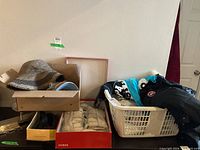 Photo showing assorted hats in box, swimsuits in laundry basket, shoe boxes including Guess brand, and clothing