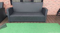 Front view of sofa frame without cushions in front of brick wall