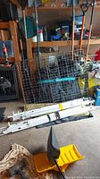 Metal dog crate and bundled white poles in garage setting with tools and supplies visible.