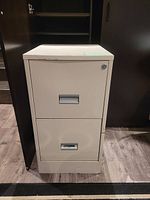 Full front view of the two-drawer beige filing cabinet showing lock on top drawer and metal handle design.