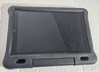 Amazon Fire HD 10.1 tablet front with screen off, inside black protective case.