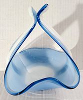 Front view of the blue art glass basket showing split handles and curved edges.