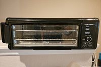 Front view of black Ninja digital air fryer oven with glass door and interior with wire racks and trays