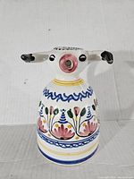 Front view of the ceramic cow-shaped pitcher showing floral decoration and cow head spout.