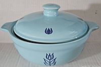 Top angled view of the blue covered bowl showing tulip design on lid and bowl body, and two side handles.